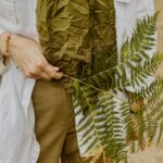 Close-up of a woman holding fern fronds, focusing on natural textures and colors.
